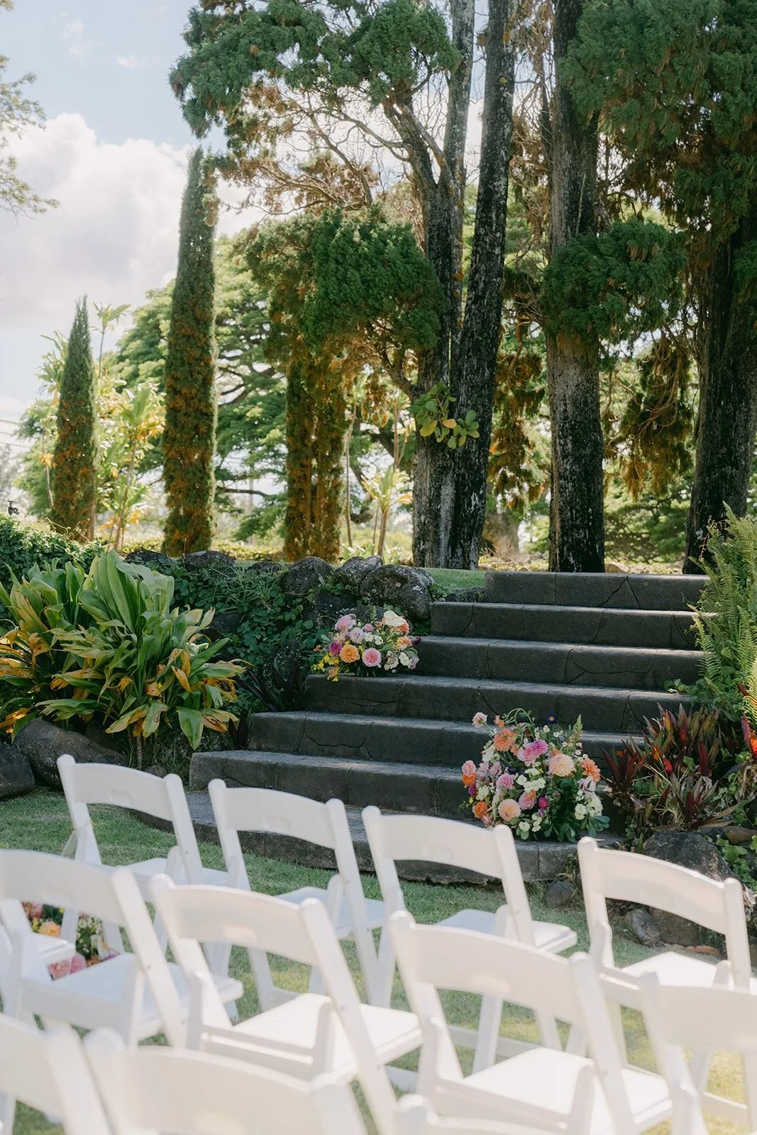A wedding ceremony setup at an outdoor stone staircase flanked by lush greenery