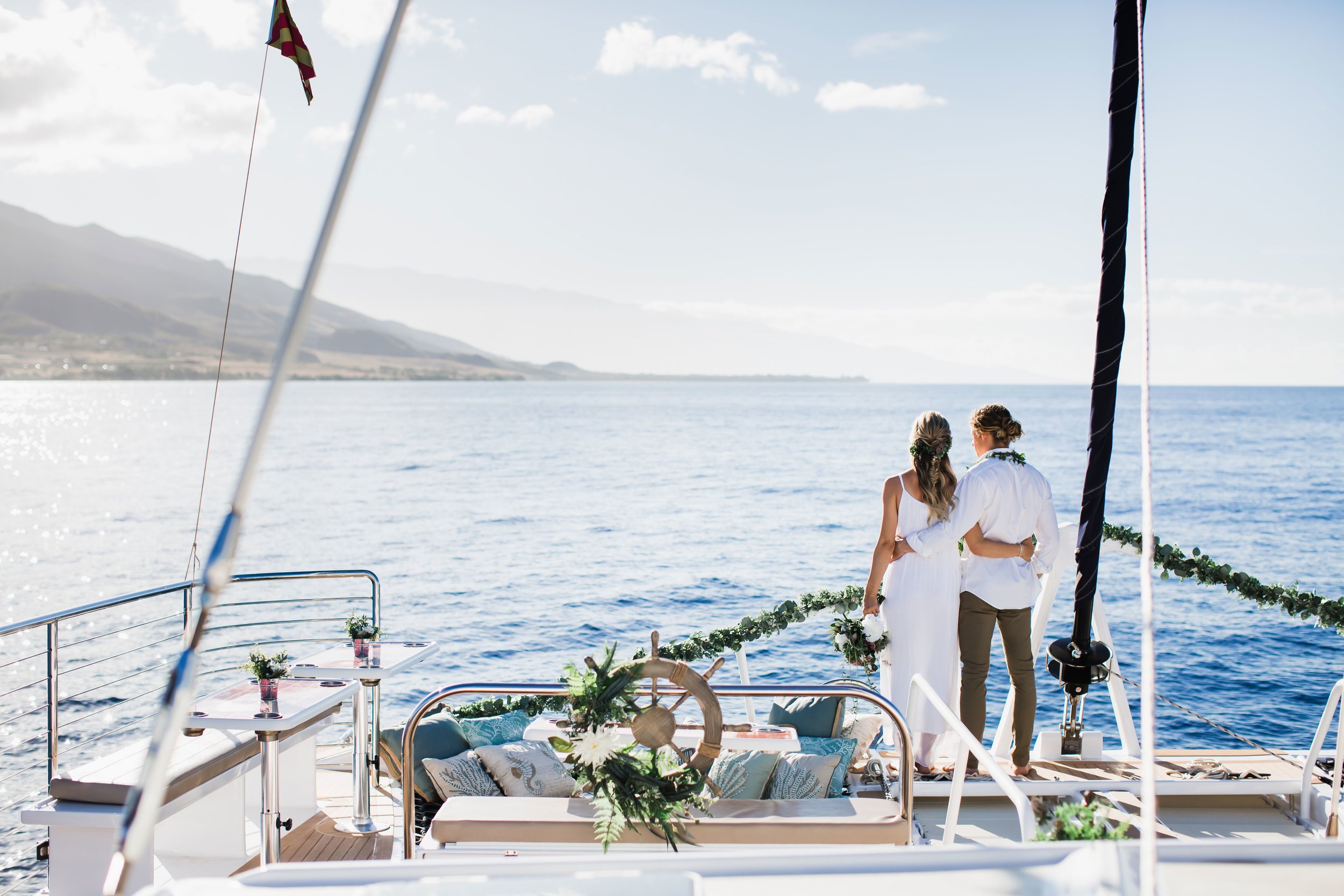 A bride and groom standing before the view from their private charter on the water.