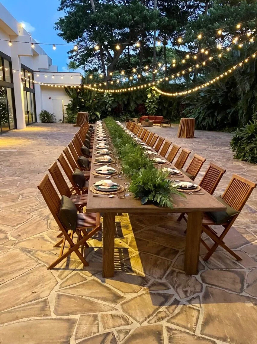 A hotel patio wedding reception tablescape beneath strung lights.