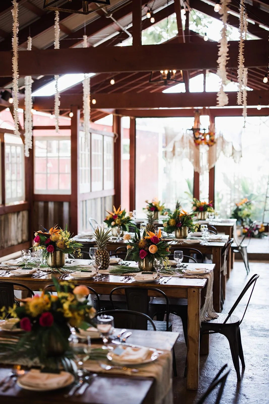 A light-filled interior tropical wedding reception beneath a high-raftered A-frame wooden ceiling.