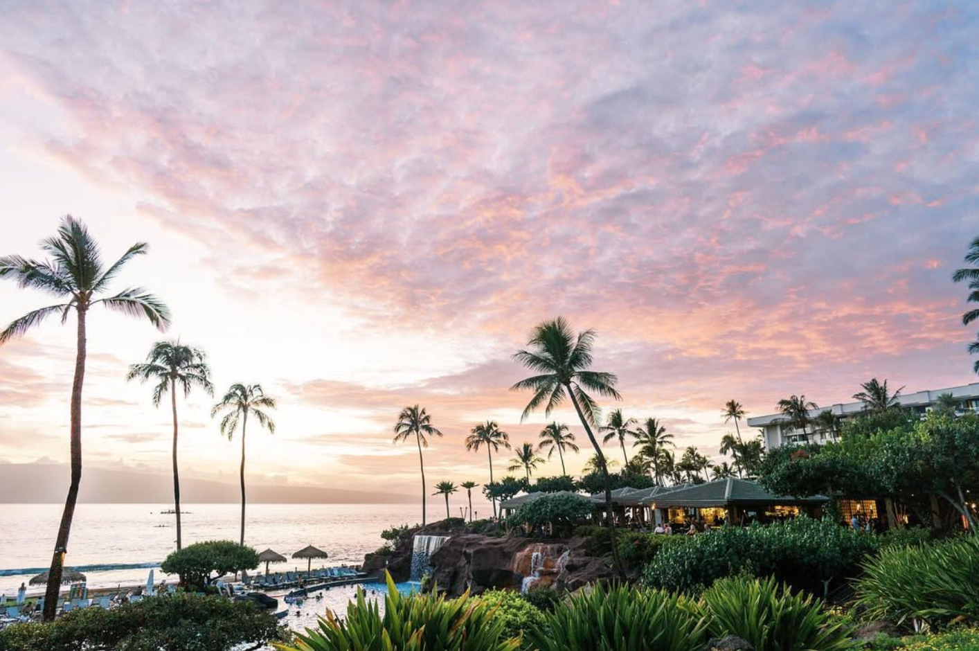 A view of the exterior of the Hyatt Regency Maui beneath a pastel sunset.