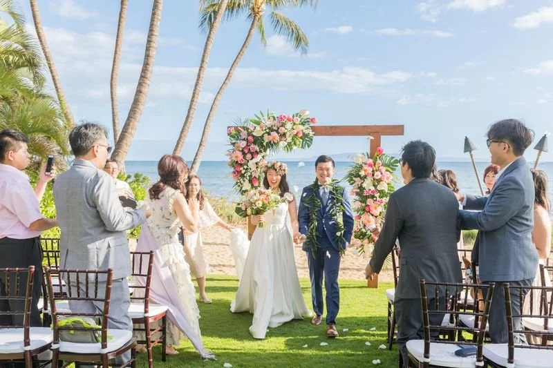 A bride and groom walking down the aisle at their tropical, beachy wedding