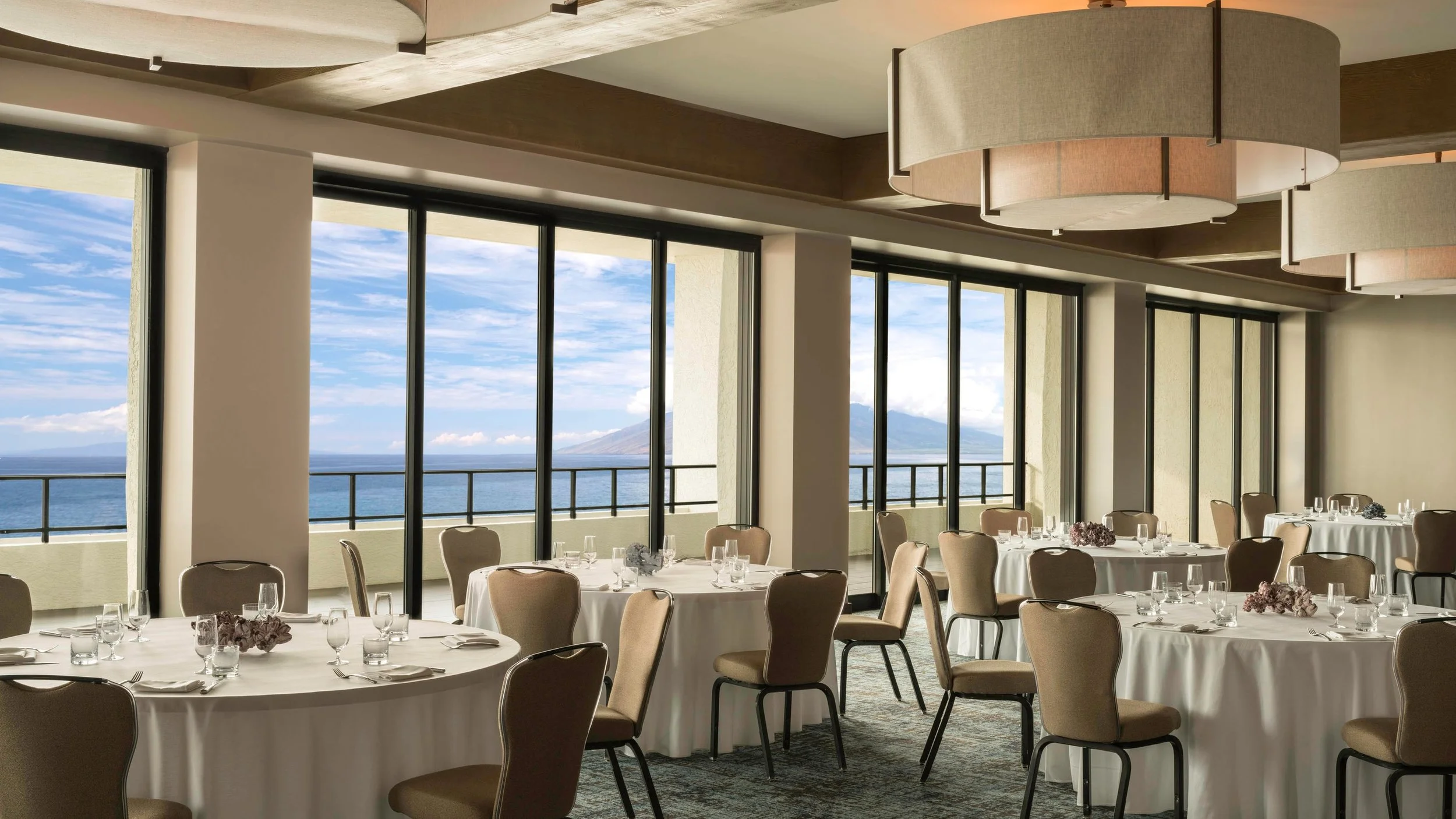 A dining ballroom with a vast view of the ocean and Hawaiian islands.