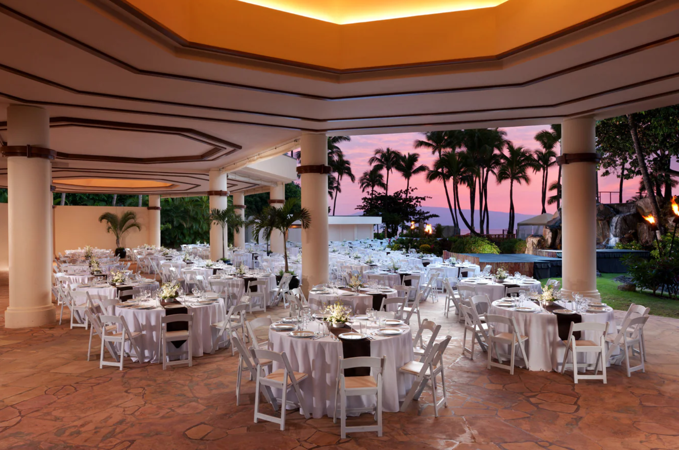 A patio wedding reception with a view of a brilliant tropical sunset.