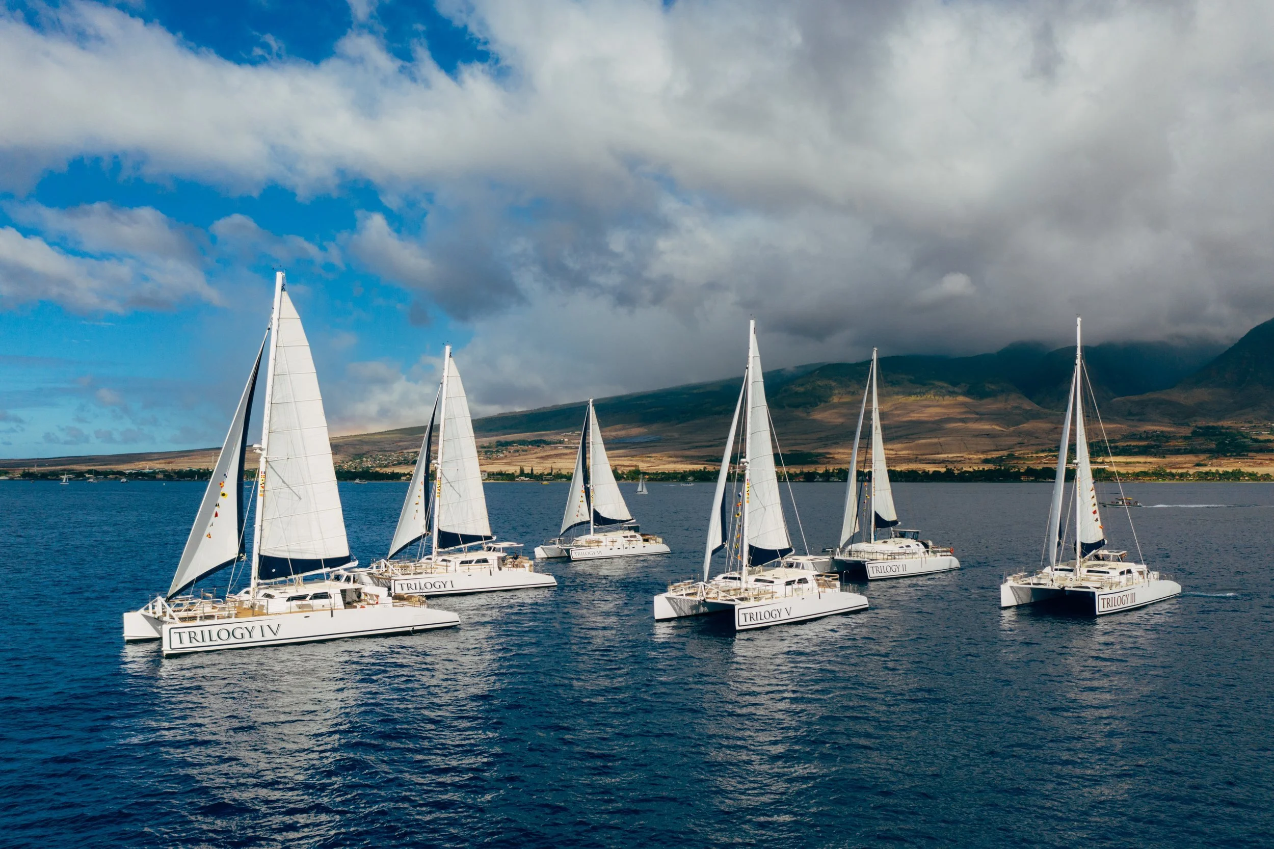 Trilogy's five vessels on the water with the island of Maui int he background.