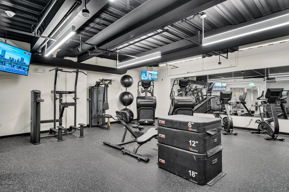 A clean, modern fitness room for club members. With large mirrors and an assortment of equipment.