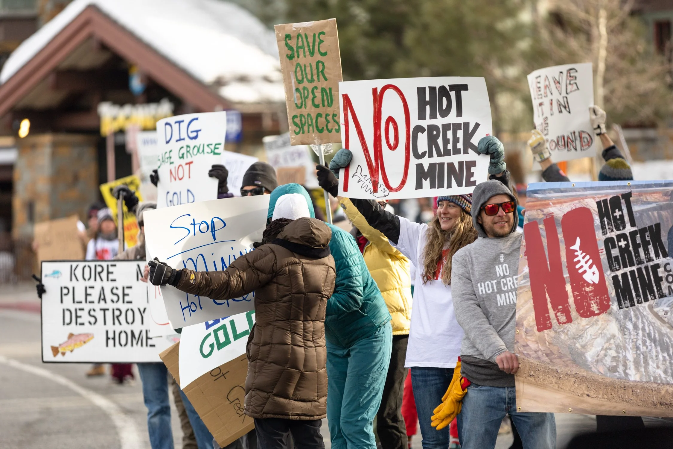A group of people participating in a protest march holding various signs advocating for environmental conservation and stopping harmful activities like mining and destruction.