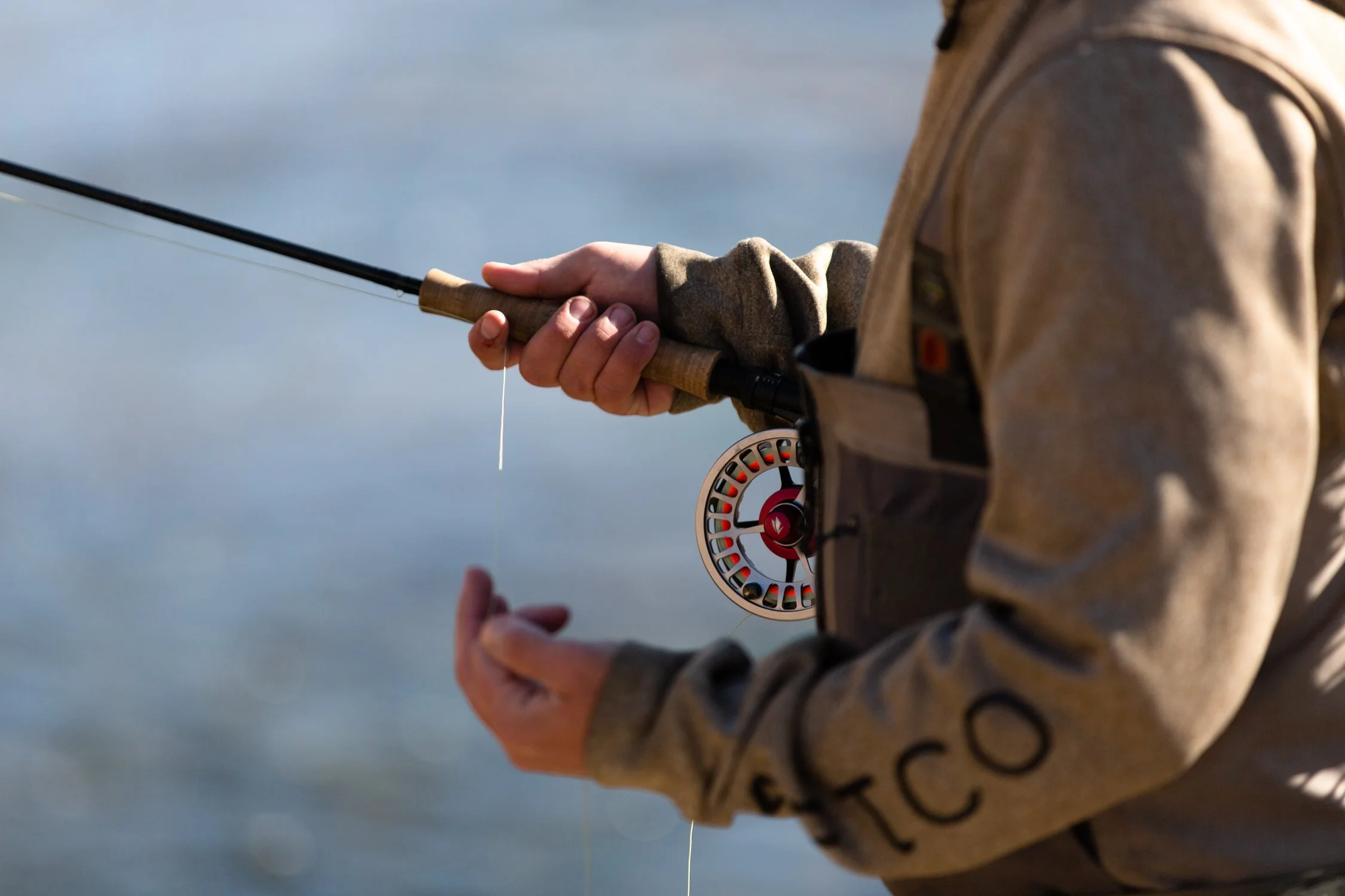 Person holding a fishing rod near a body of water.