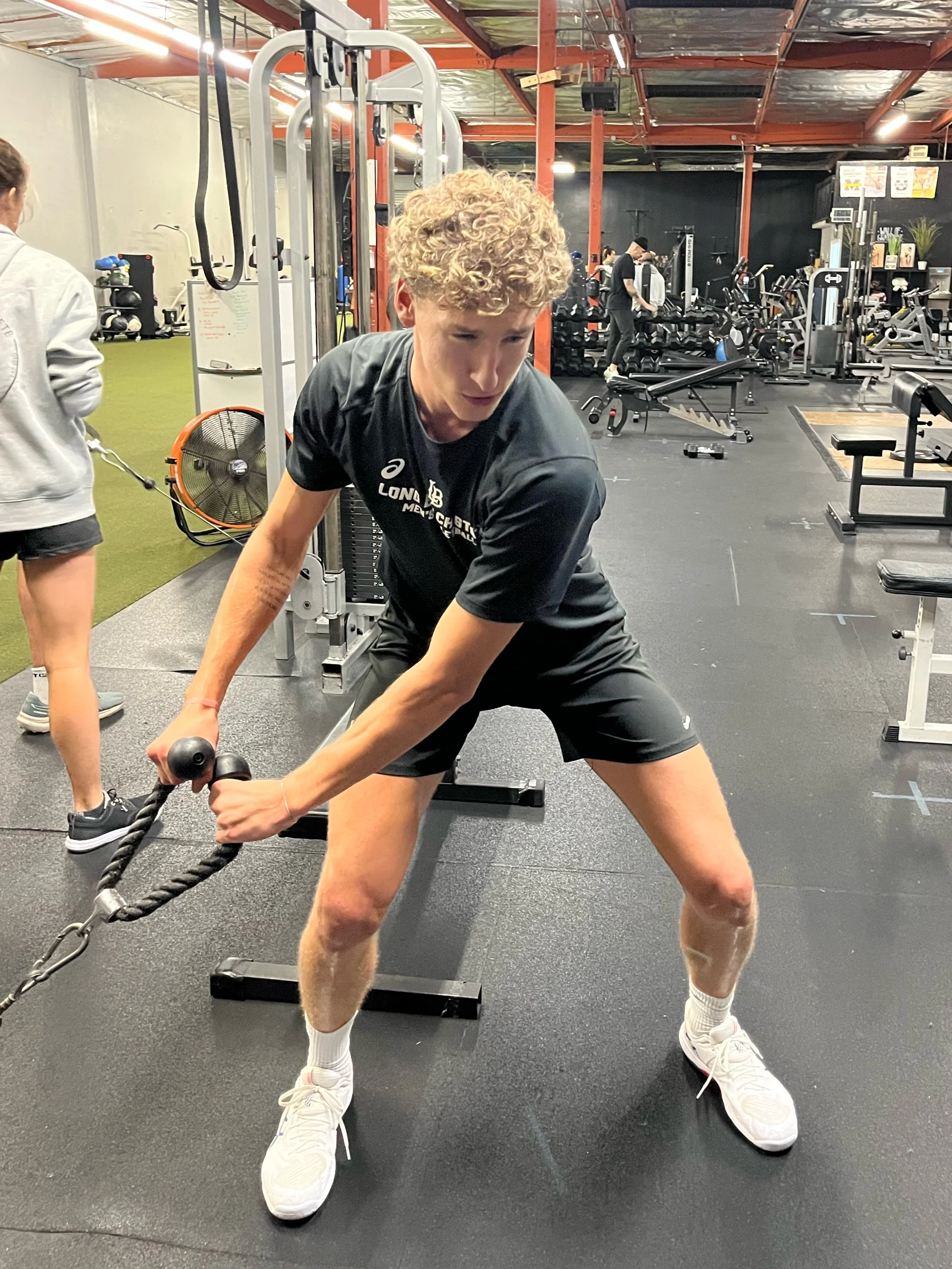 Volleyball athlete performing a cable anti-rotation core exercise for core stability and injury prevention during a strength and conditioning session at The Healthy Athlete sports performance training facility in Huntington Beach, California.