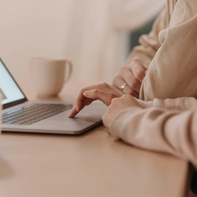 Person using a laptop with a coffee mug in the background.