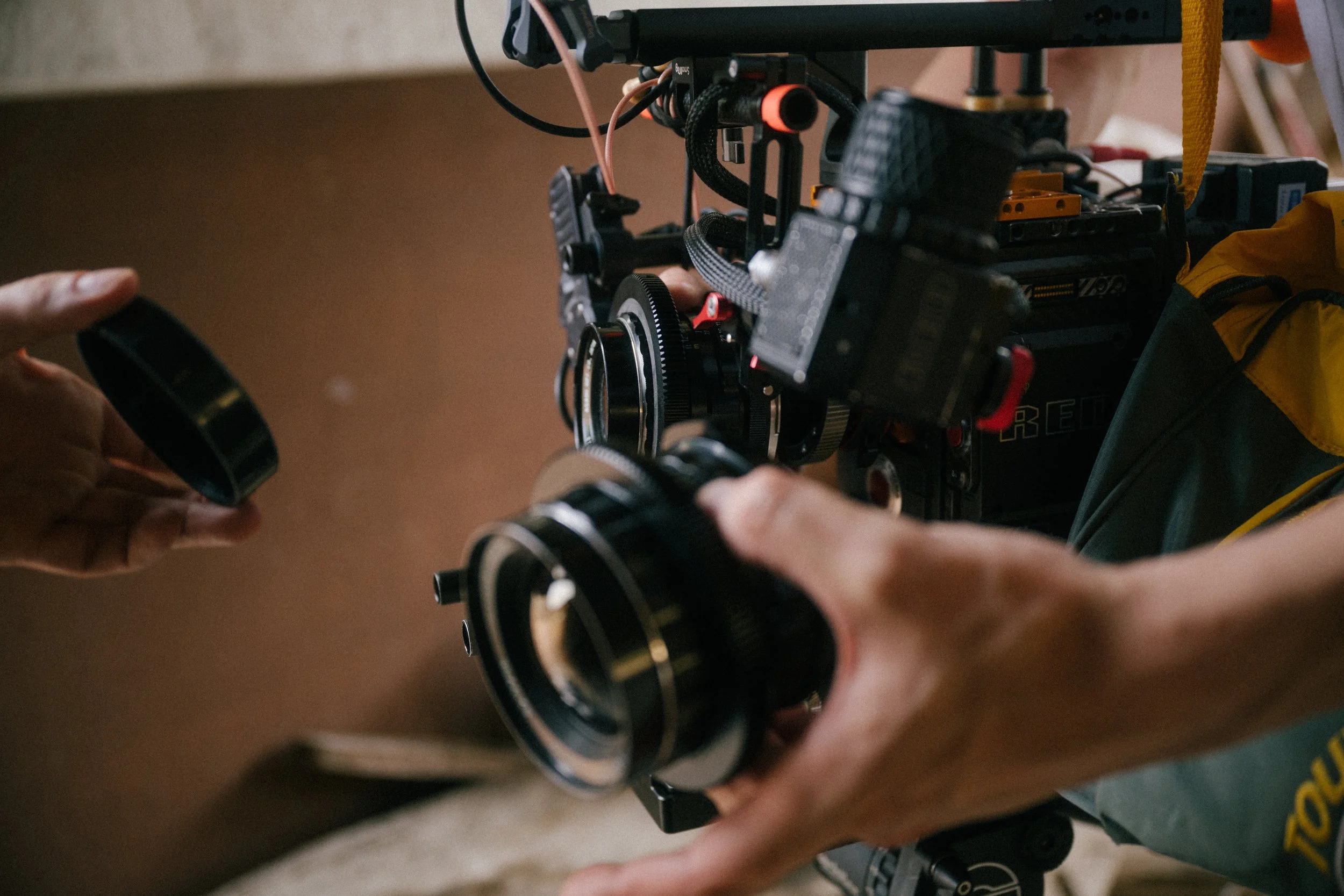 Two hands handling a camera with various components and cables attached, likely on a film or video set.