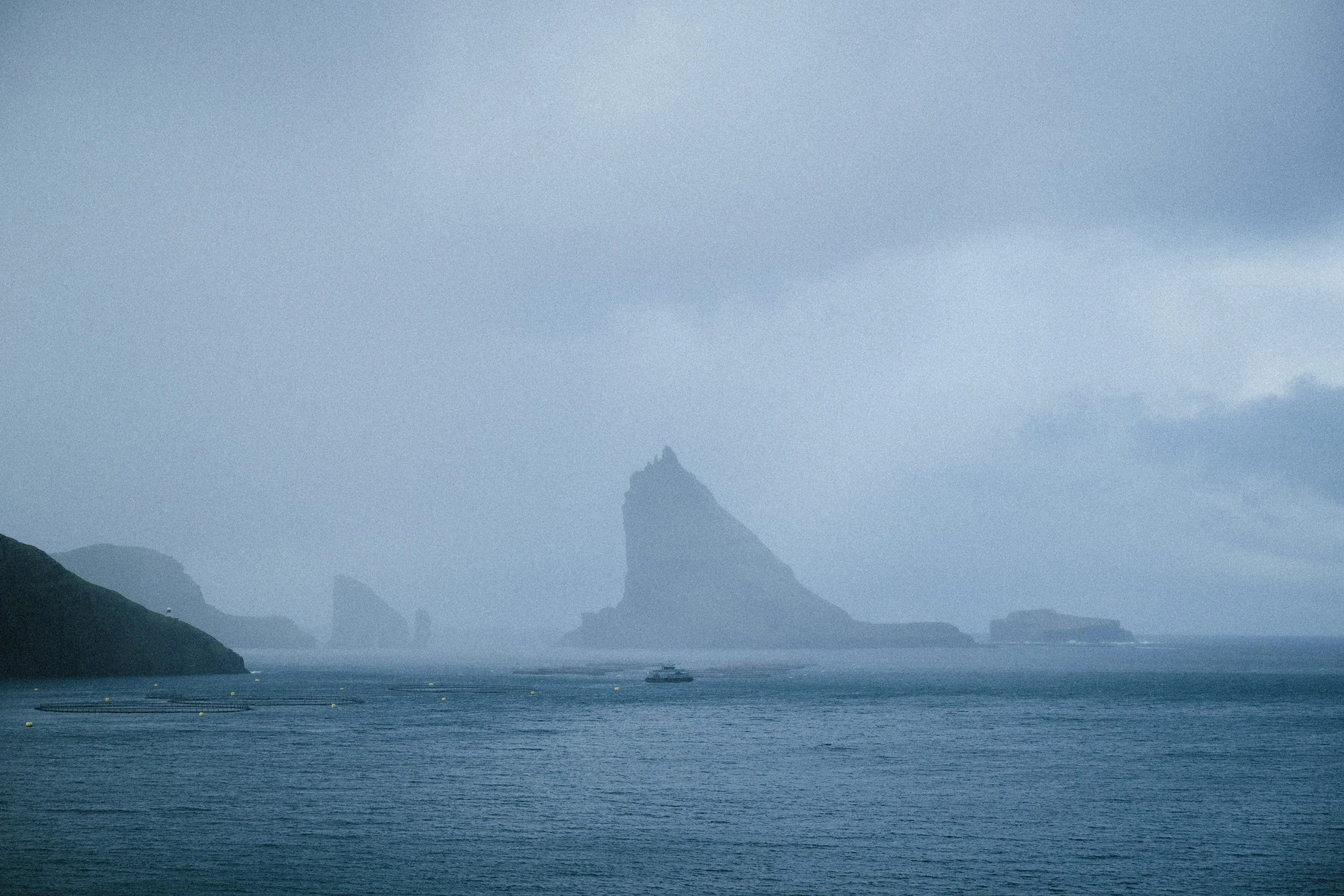 Overcast sky over a body of water with distant islands and a boat