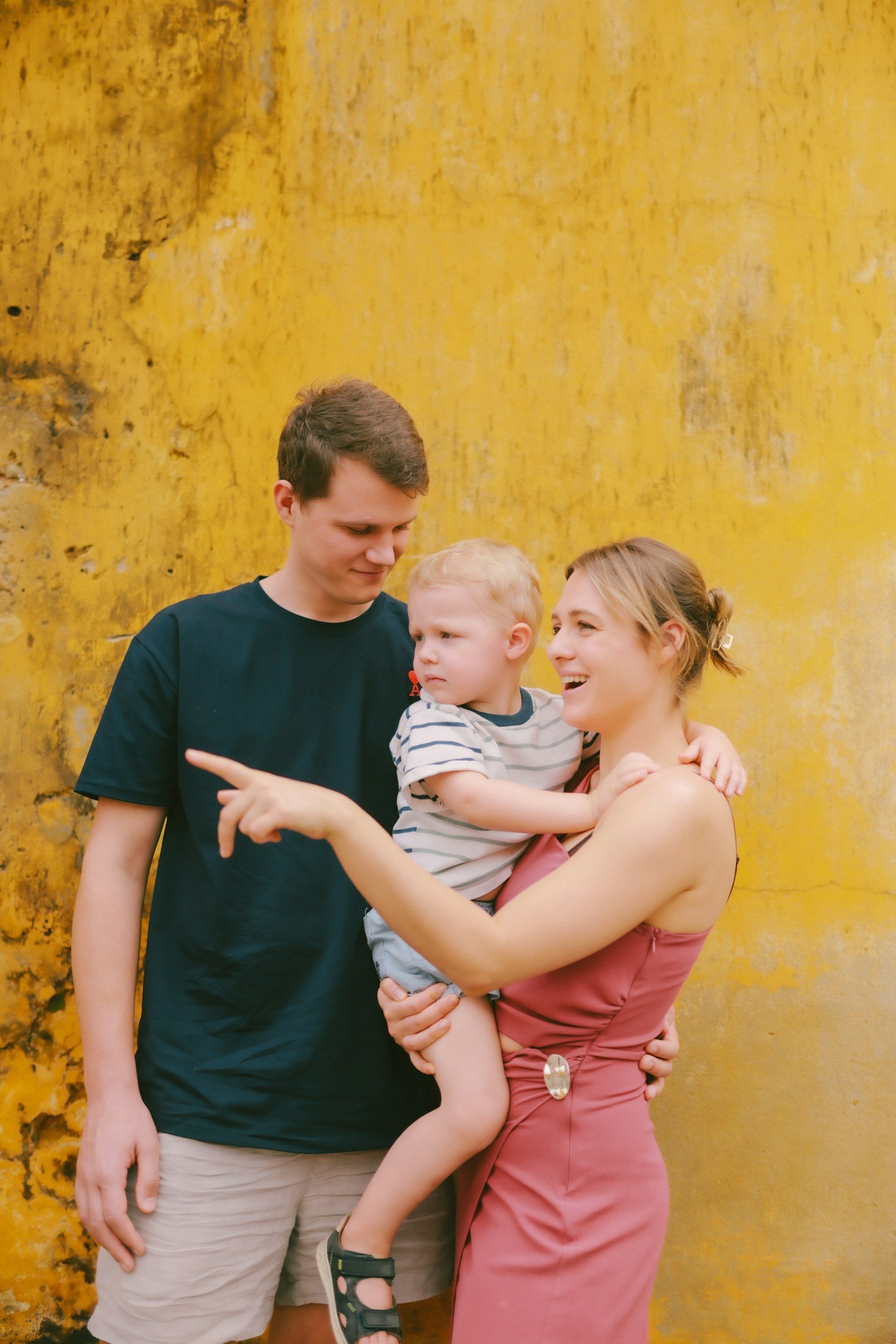 Family of three smiling and pointing at something while they work on their conversation and recall skills from speech therapy
