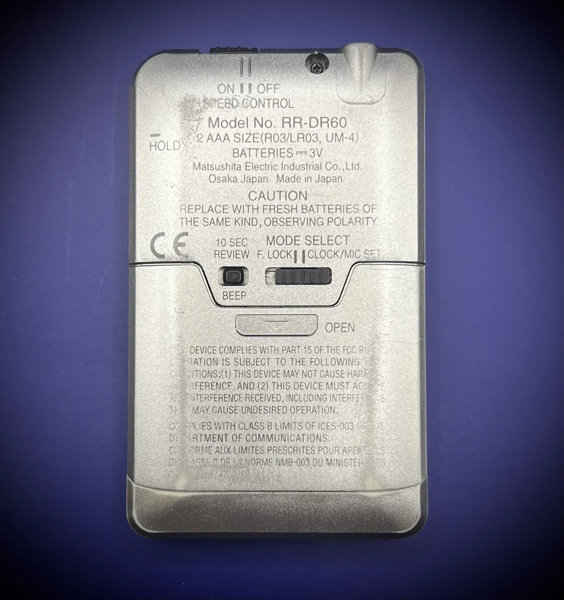 Panasonic RR-DR60 digital voice recorder back view - blue background