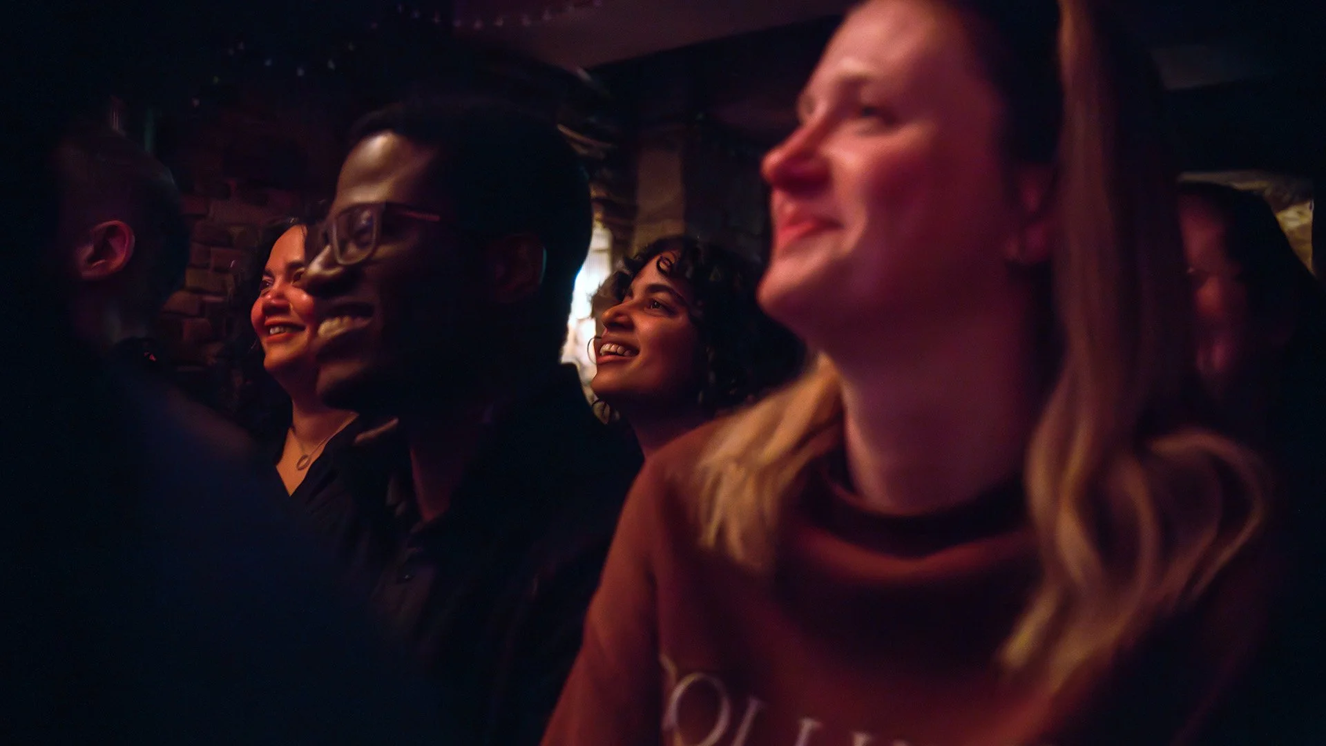 An international audience smiling and laughing during an English-language comedy night in Berlin