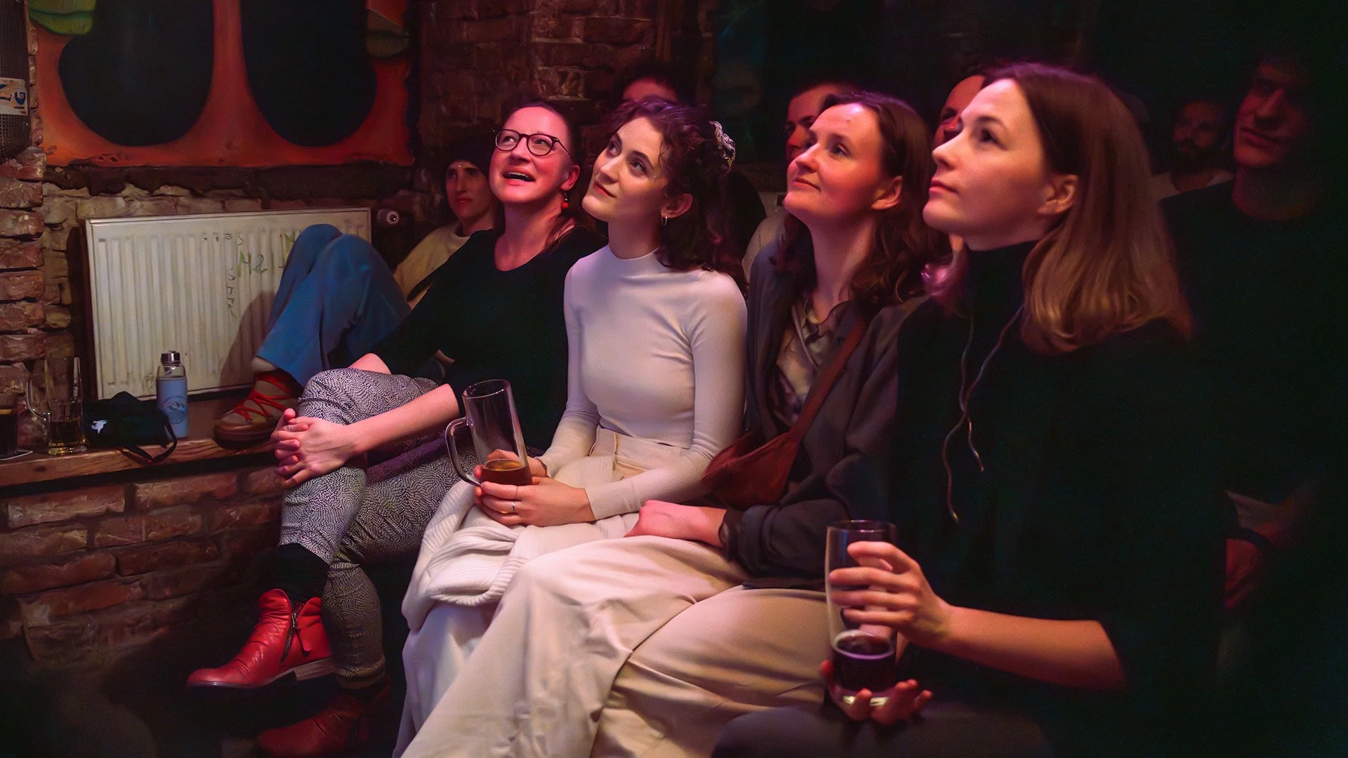 Four women in the front row smiling up at the stage during an English stand-up comedy show in Berlin