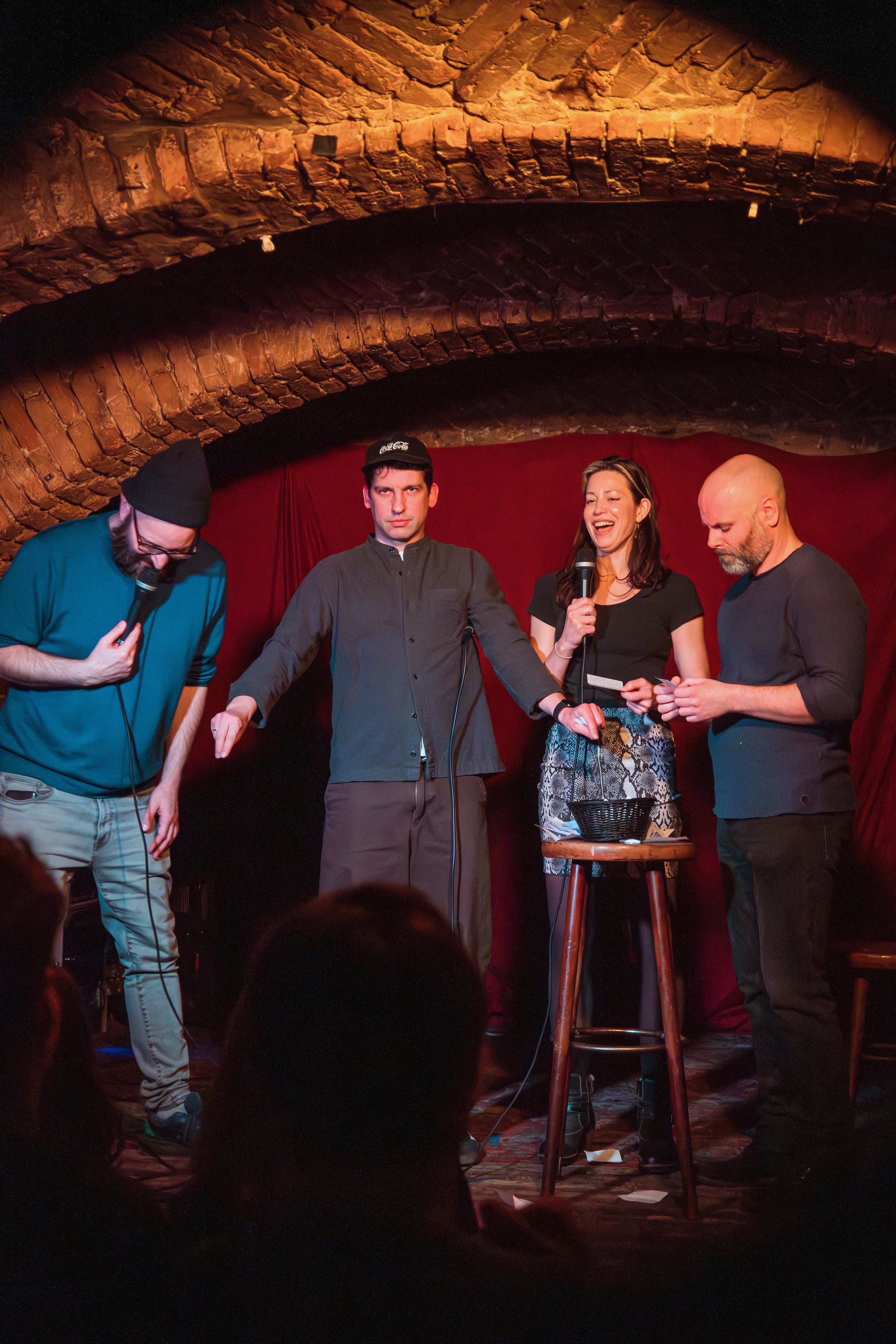 Four comedians on stage reading audience notes aloud during an interactive comedy show