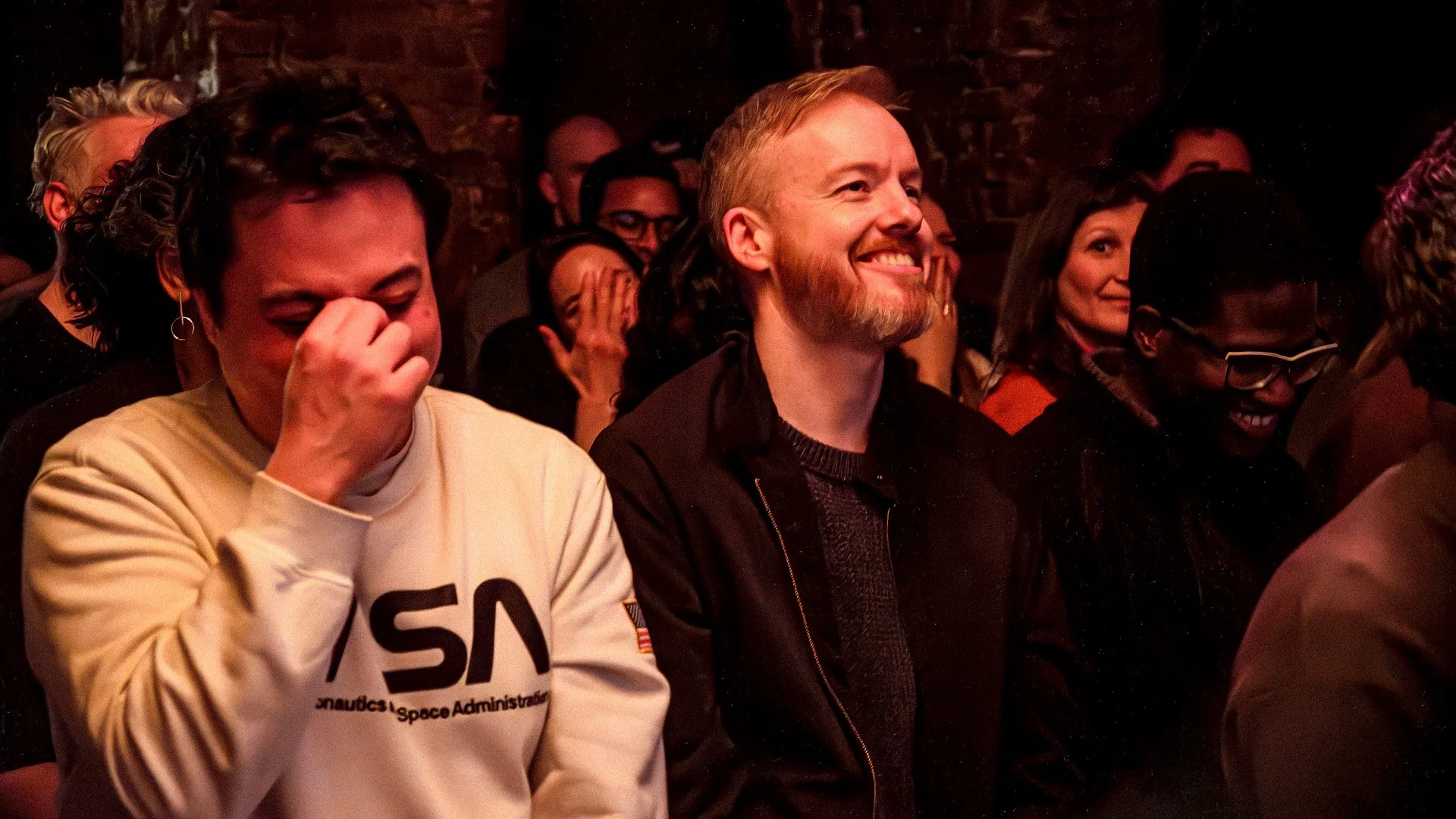 A packed basement crowd laughing together during a Darkest Thoughts comedy show in Berlin