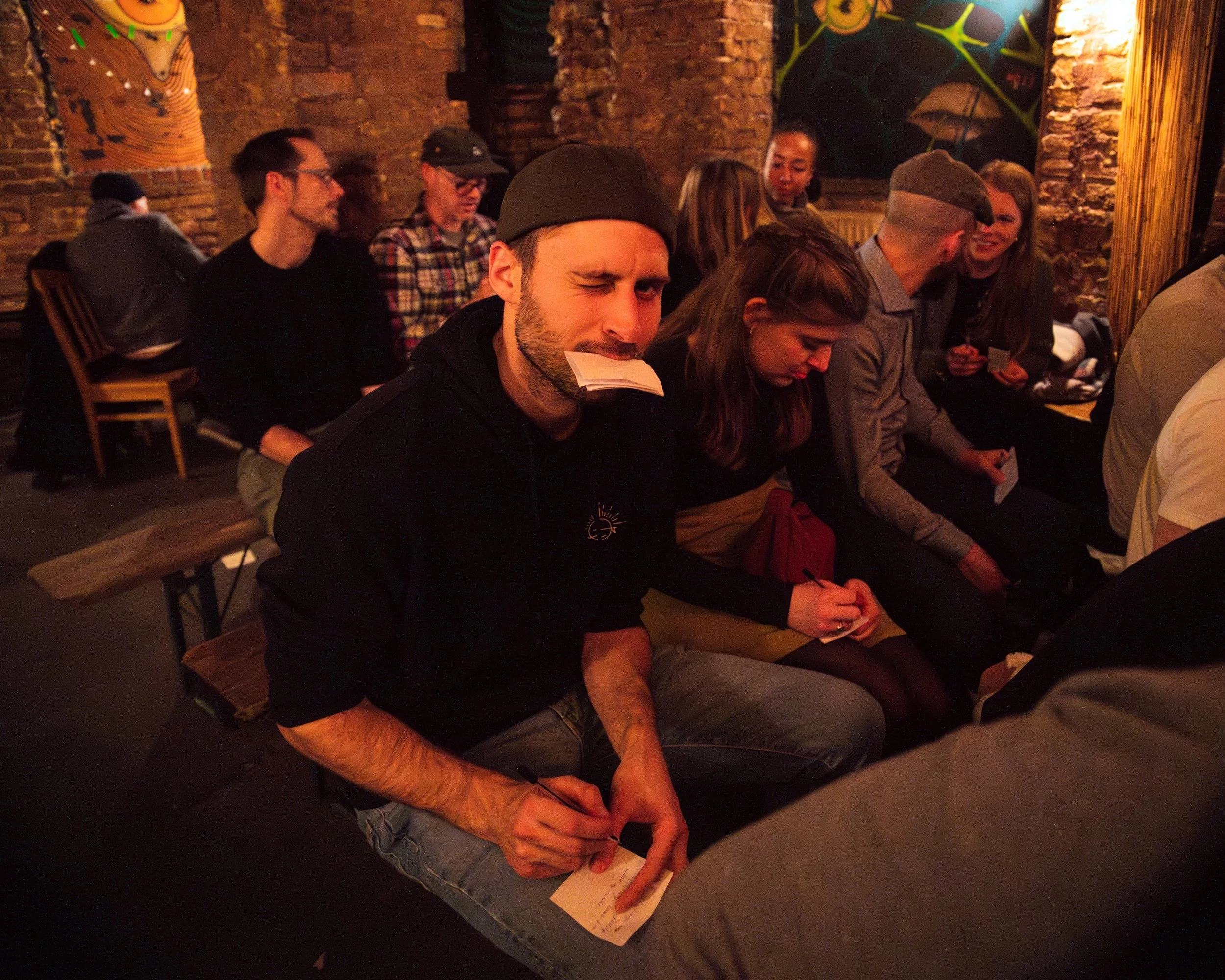 Audience member writing a suggestion on a slip of paper during Darkest Thoughts, an English comedy show in Berlin, where the crowd feeds the comedians their material