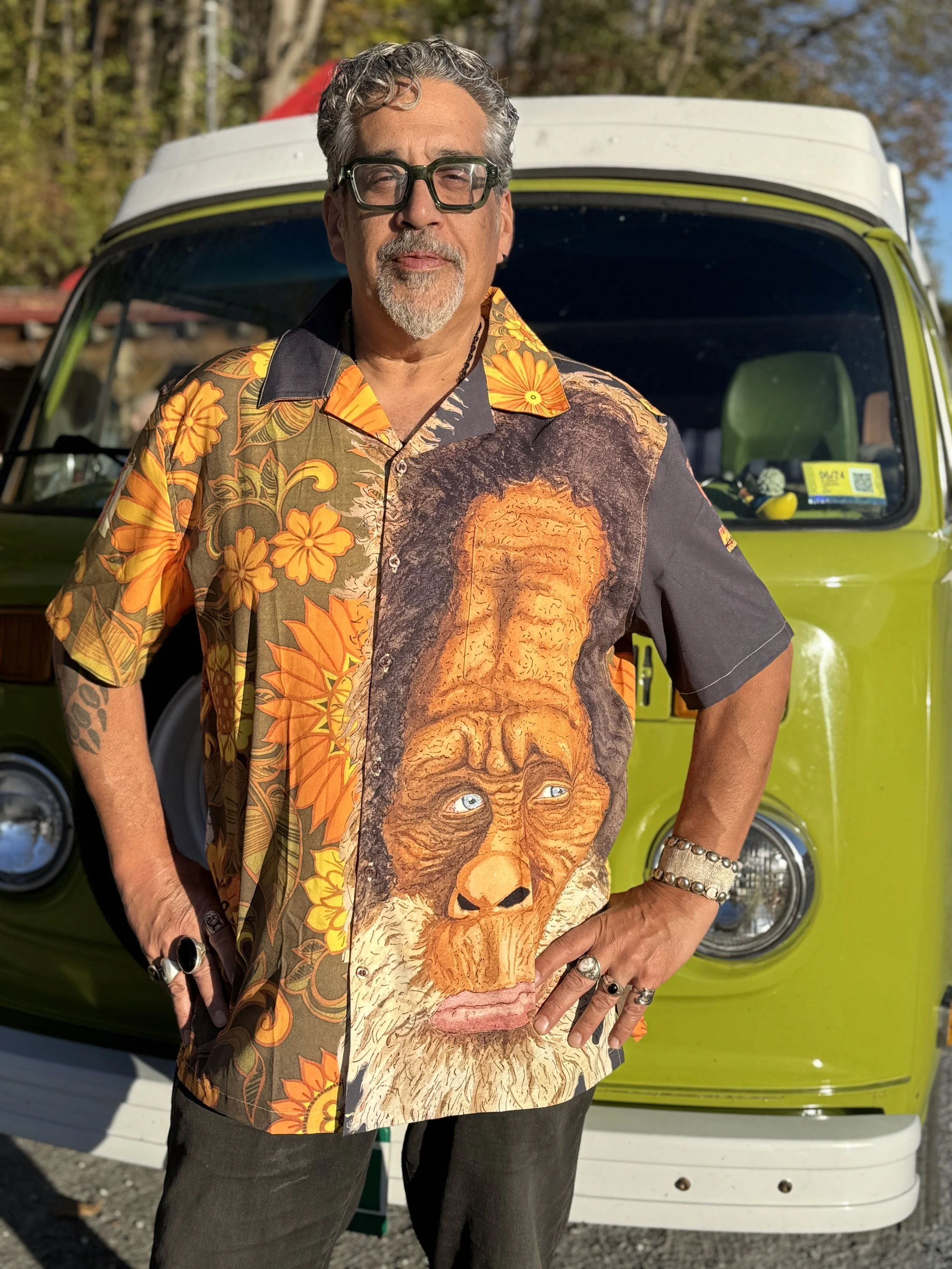 Man wearing a Hawaiian shirt featuring a watercolor portrait of Harry from Harry and the Hendersons with a vintage-inspired green and orange floral pattern. Harry’s face appears large on both the front and back of the shirt.