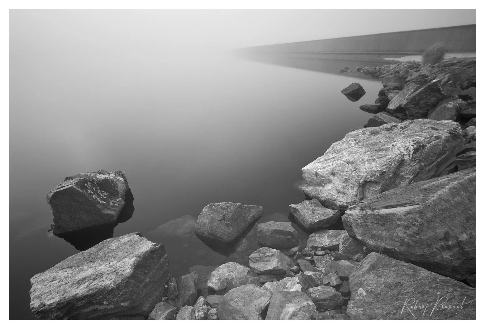 infrared b&w image where dam wall disappearing into distant fog