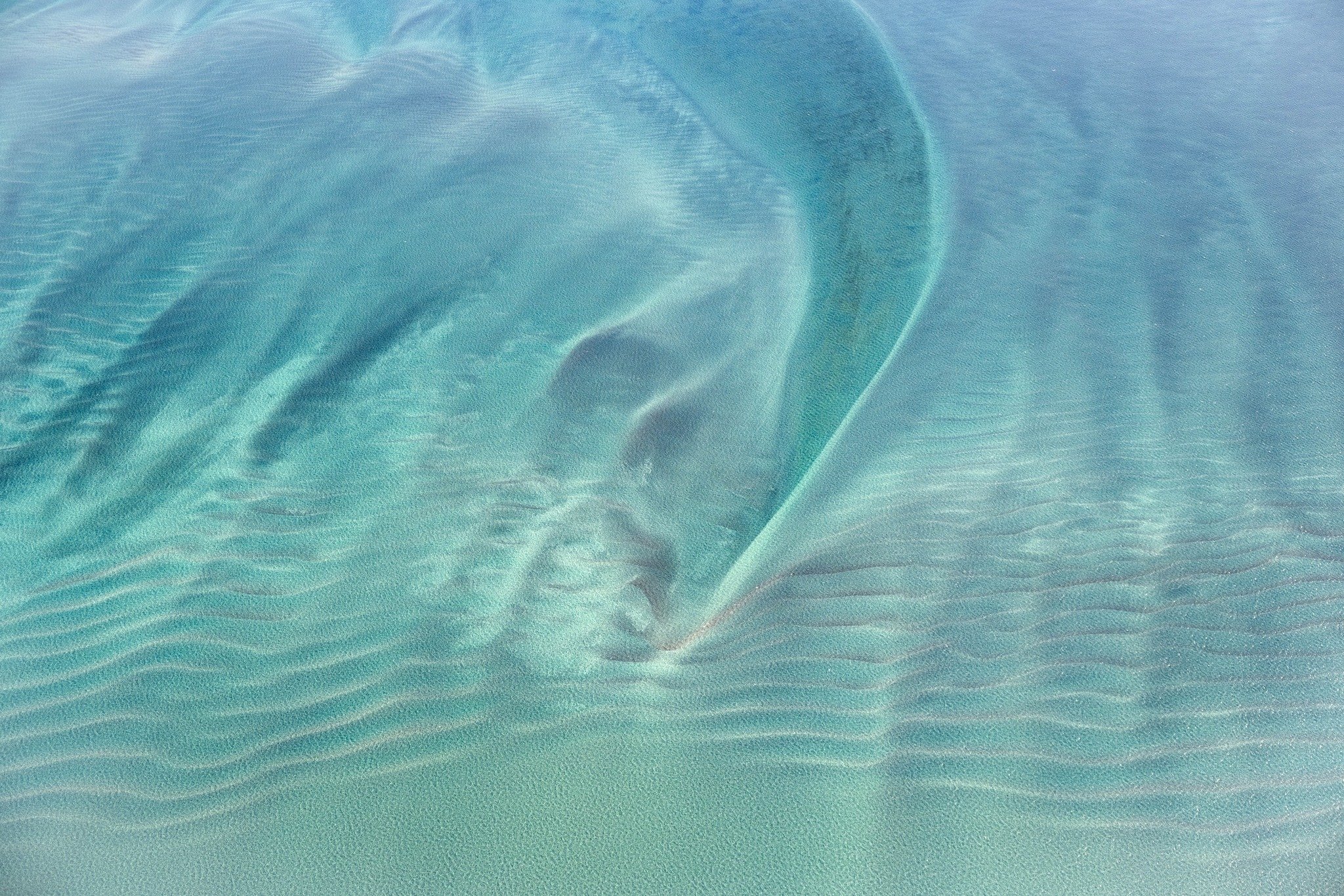 &lsquo;Shallow Whisper&rsquo; 2026
The ocean has something to say, and it&rsquo;s saying it very quietly. That sweeping curve is a sandbank &mdash; and the ripples radiating out beneath crystal-clear teal water are the sea&rsquo;s own handwriting. Yo