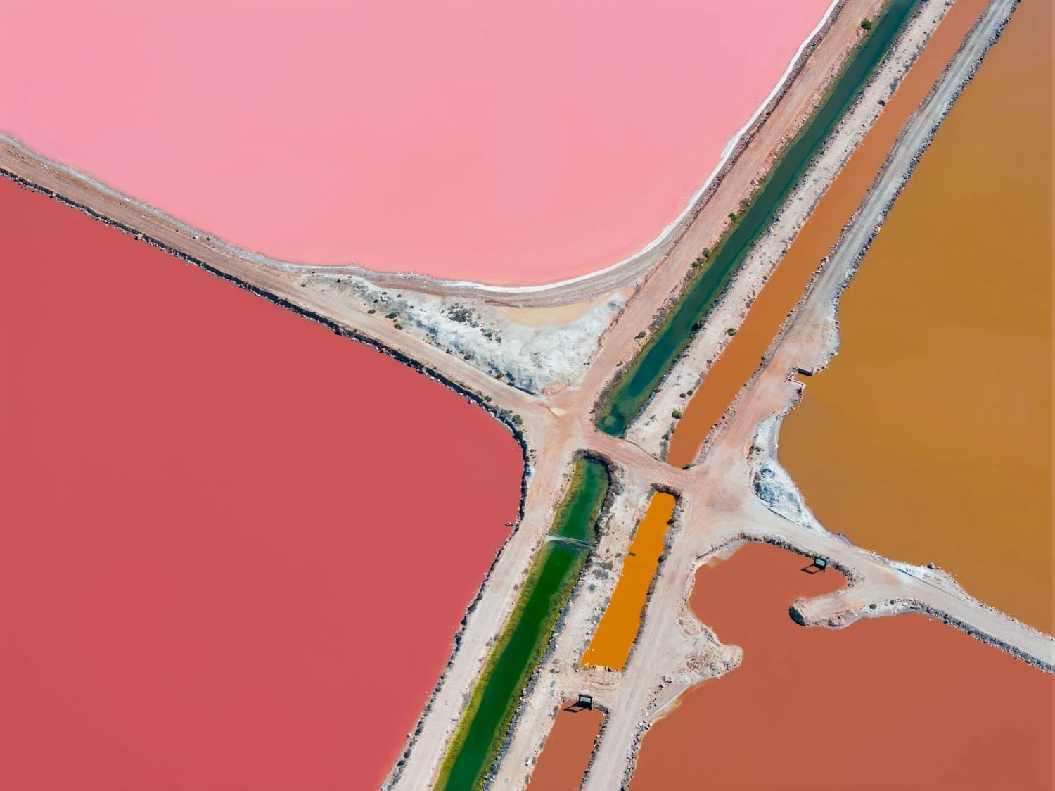 Rose Quadrant — Aerial fine art photograph of salt pans in blush pink, coral, and amber tones, divided by pale causeways and a teal-green canal, with a striking block of saturated orange breaking the palette; bold, graphic statement piece for a moder