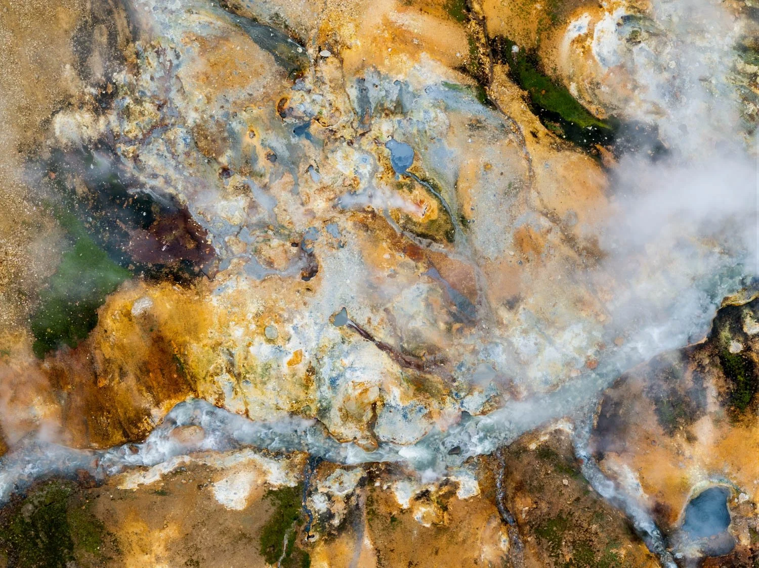 Geothermal Paints.  A geothermal spring in Iceland from above — an extraordinary colour field of amber, gold, grey-white mineral, dark earth, green algae and drifting steam. The earth's own palette. Unique large format wall art for serious art collec