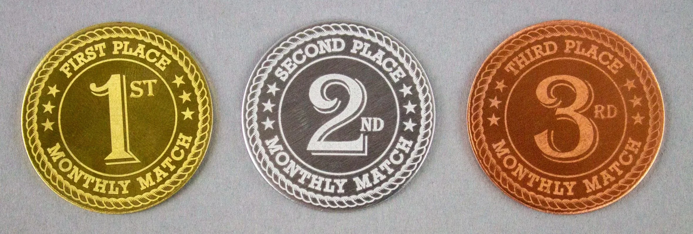 SASS Monthly Match Award Coins with laser-engraved first, second, and third place designs.