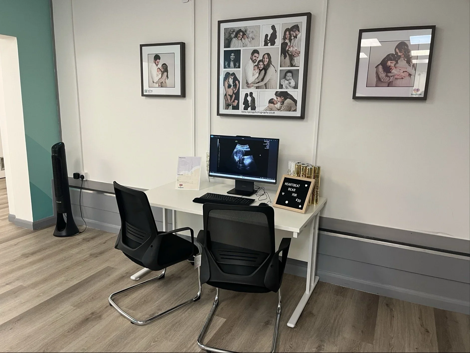 Consultation area with ultrasound image display, seating, and heartbeat bear keepsakes at the Imaginatal pregnancy ultrasound clinic.