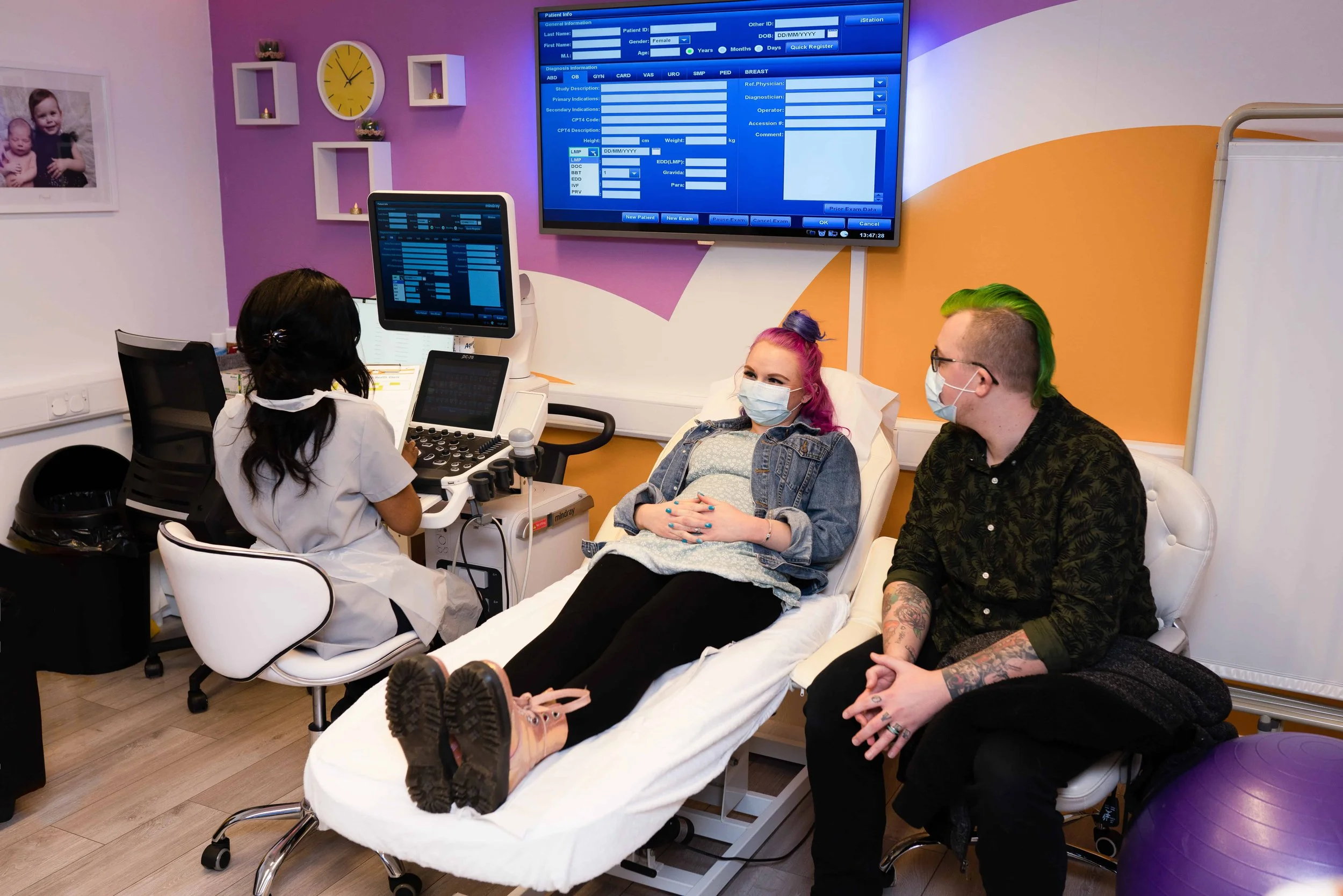 Patient having a private ultrasound scan while a sonographer and a companion sits beside them in the clinic room.