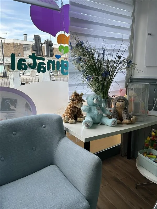 Toys and a flower arrangement displayed on a table in the waiting area of the Imaginatal clinic.