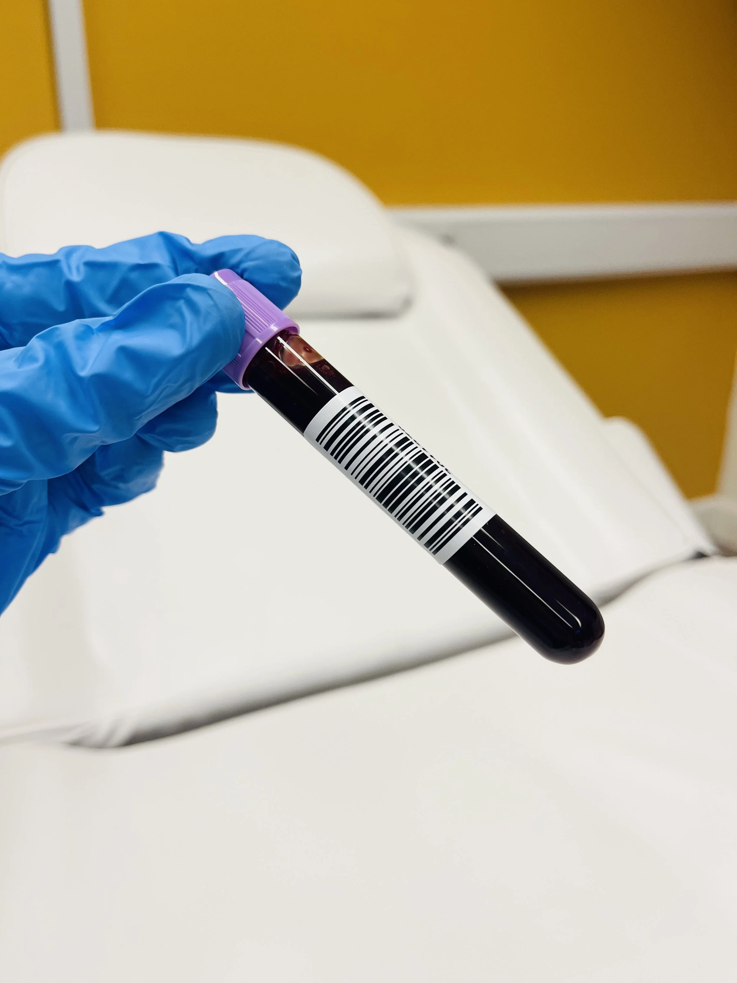 Gloved hand holding a labelled vial of blood ready for a NIPT test at Imaginatal
