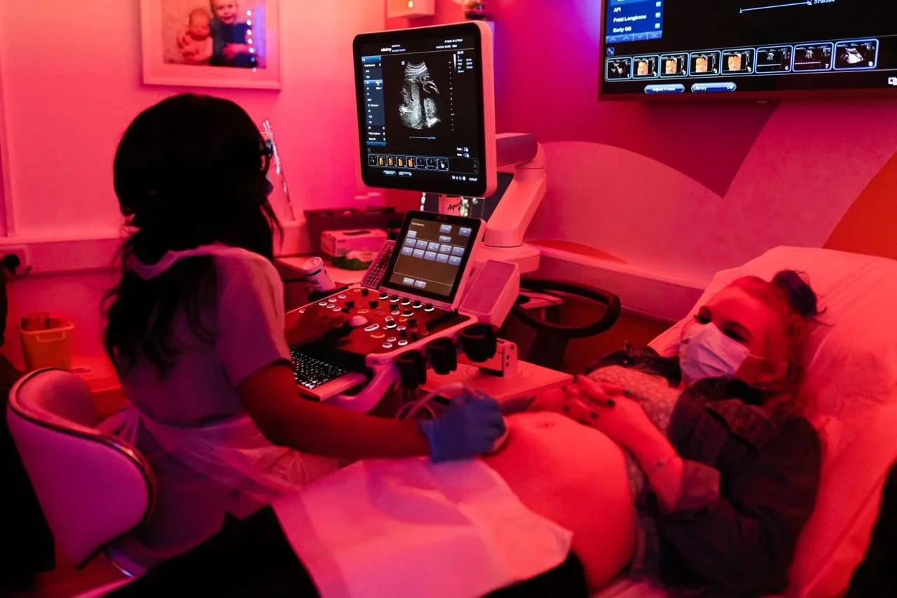 Pregnant woman having a bonding ultrasound scan in a softly lit Imaginatal clinic room while viewing the baby scan on screen