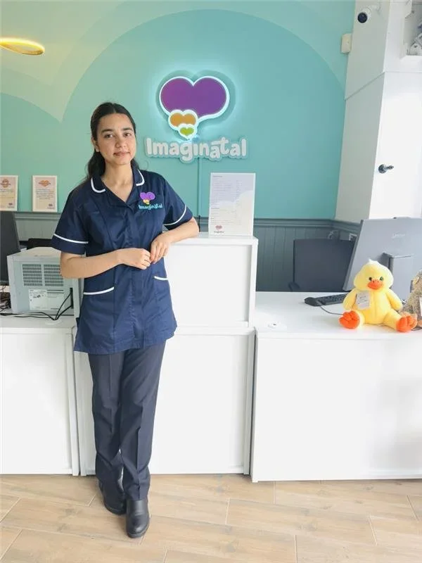 Sonographer standing at the reception desk of the Imaginatal pregnancy ultrasound clinic, welcoming patients.