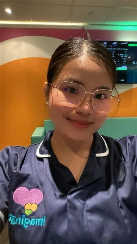 Imaginatal sonographer wearing a navy uniform in a private ultrasound clinic, smiling in the reception and scan area