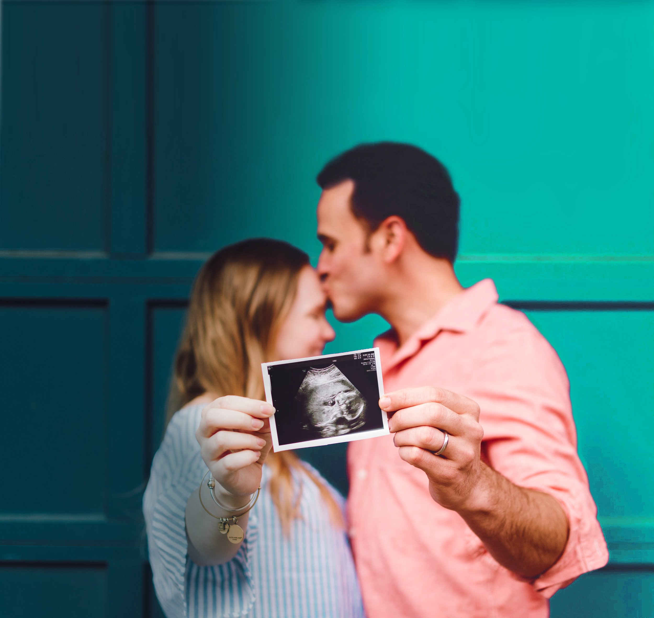 Close-up of a couple holding an ultrasound photo, with the baby scan in focus.