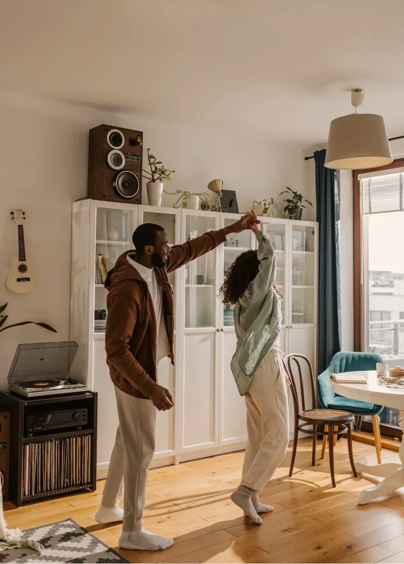 Two people dancing in a brightly lit apartment.