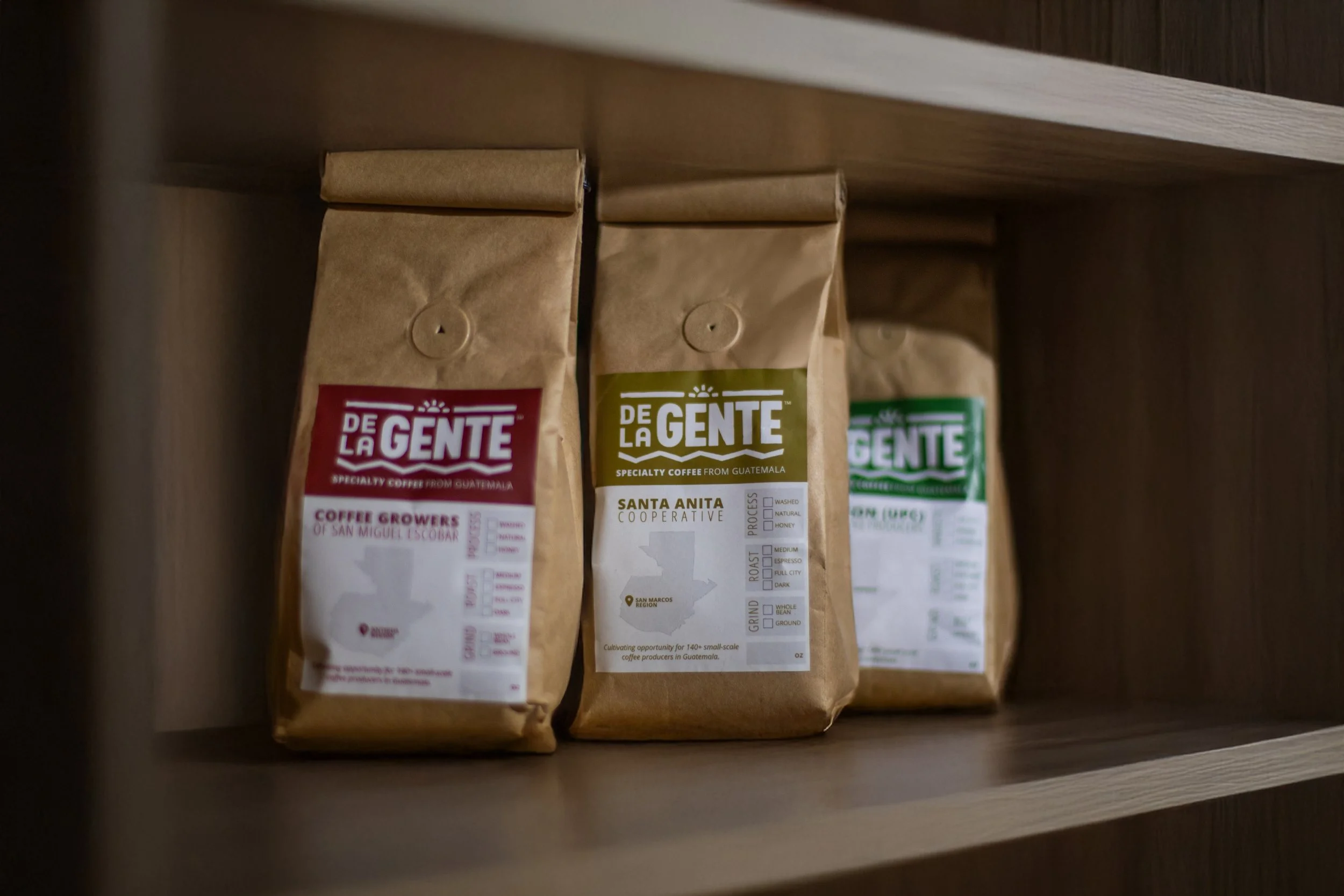 Bags of De La Gente roasted coffee beans on a shelf | coffee roasting