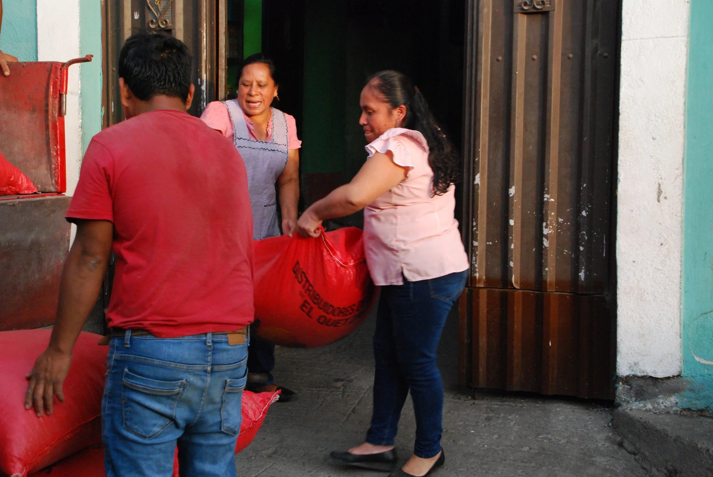 Two women coffee producers loading truck with green coffee sacks to drive them to exporter