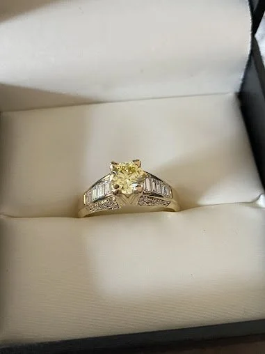 A stunning yellow diamond memorial ring set in gold, accented with sparkling baguette diamonds along the band.