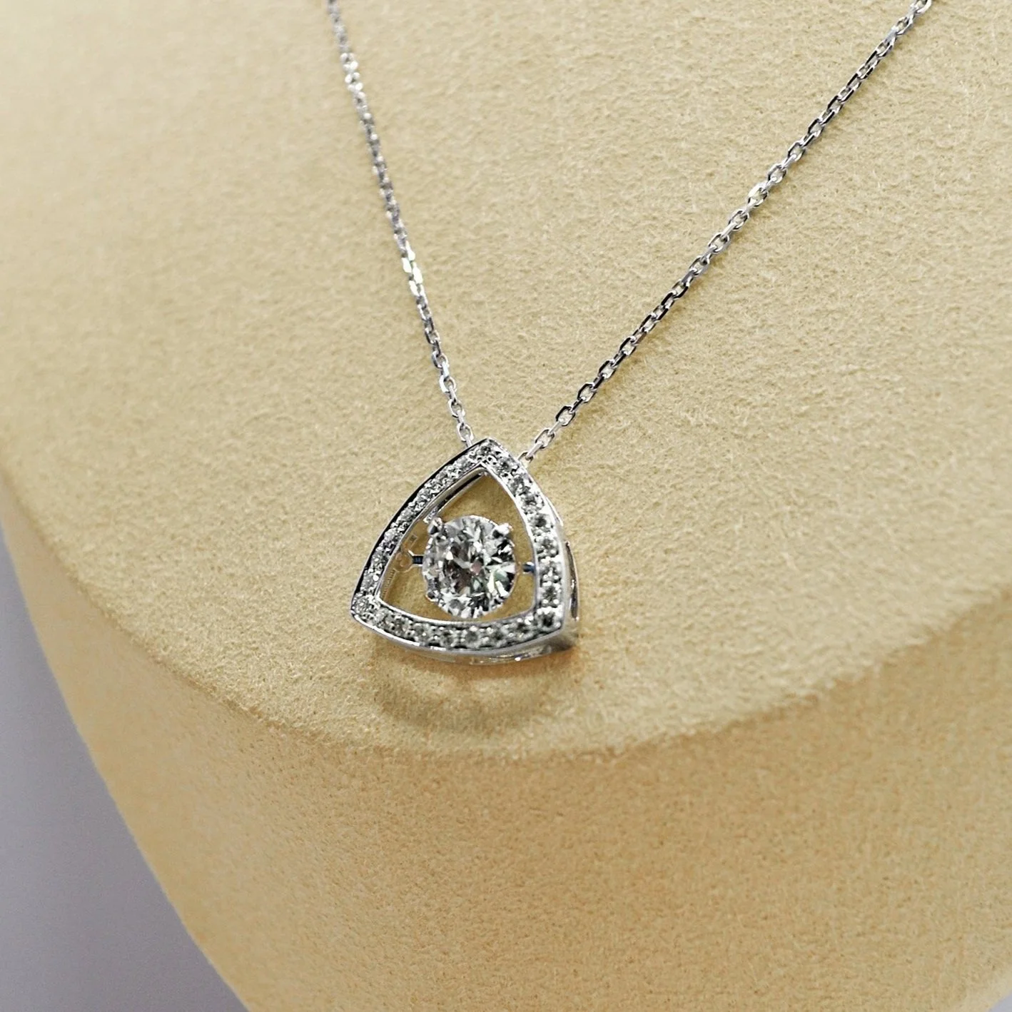 A white gold triangle pendant adorned with a central cremation diamond, surrounded by shimmering diamonds