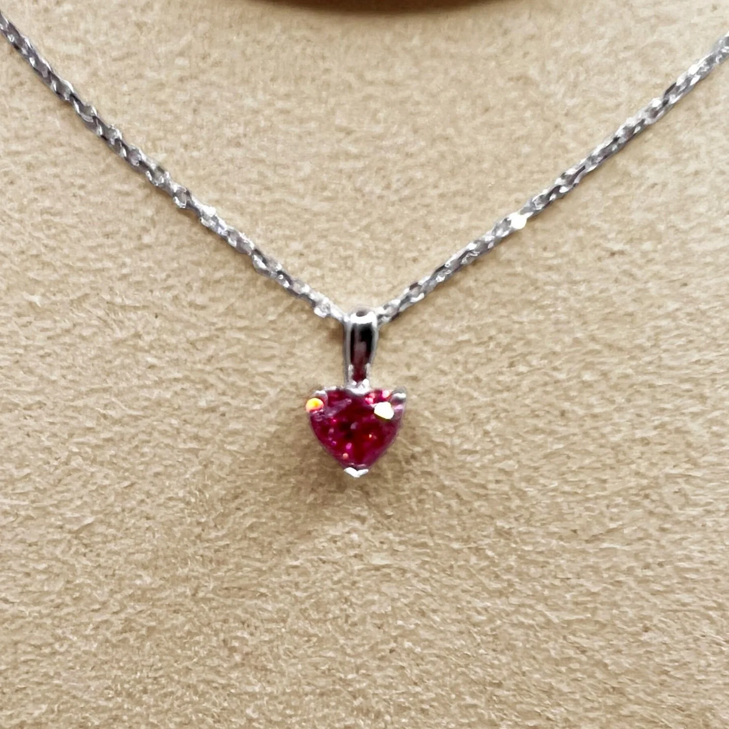 A white gold necklace with a heart-shaped pink diamond