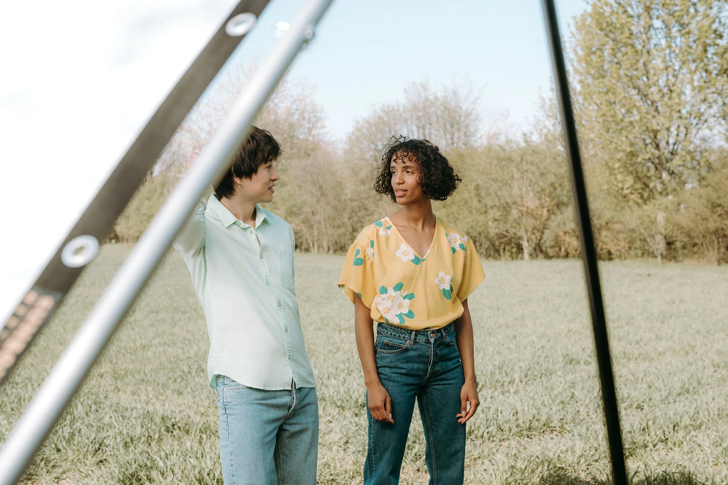 Making-Of vom Outdoor-Fotoshooting: Ein Männermodel und ein Frauenmode, beide im Sommerlook, unterhalten sich auf einer Wiese.