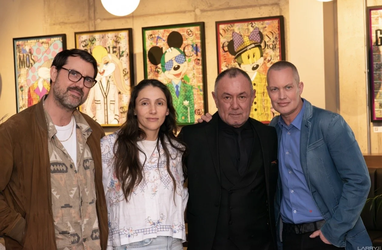 Four people standing in front of colorful art at an art gallery.