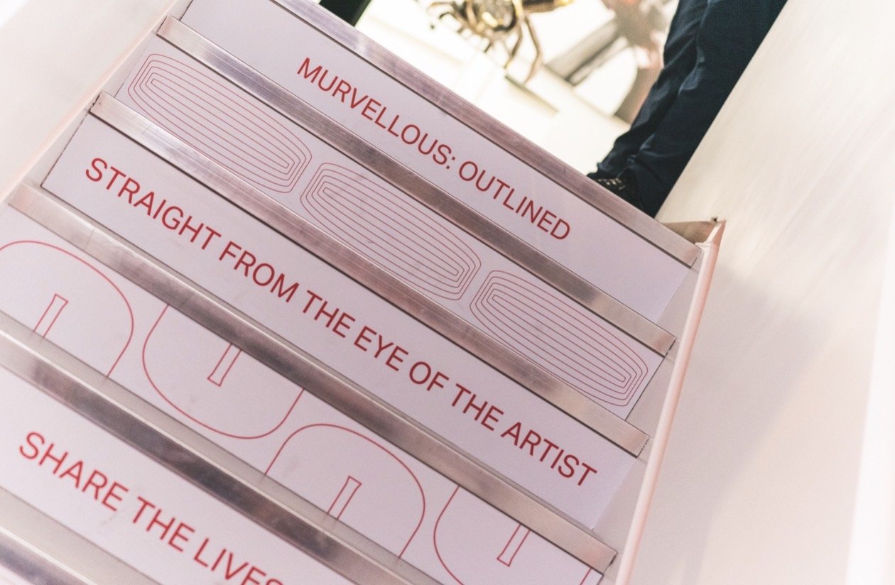 A display stand with labels in red text, including one that says 'Murvellous: Outlined' and another that says 'Straight from the Eye of the Artist,' with additional sections and designs.