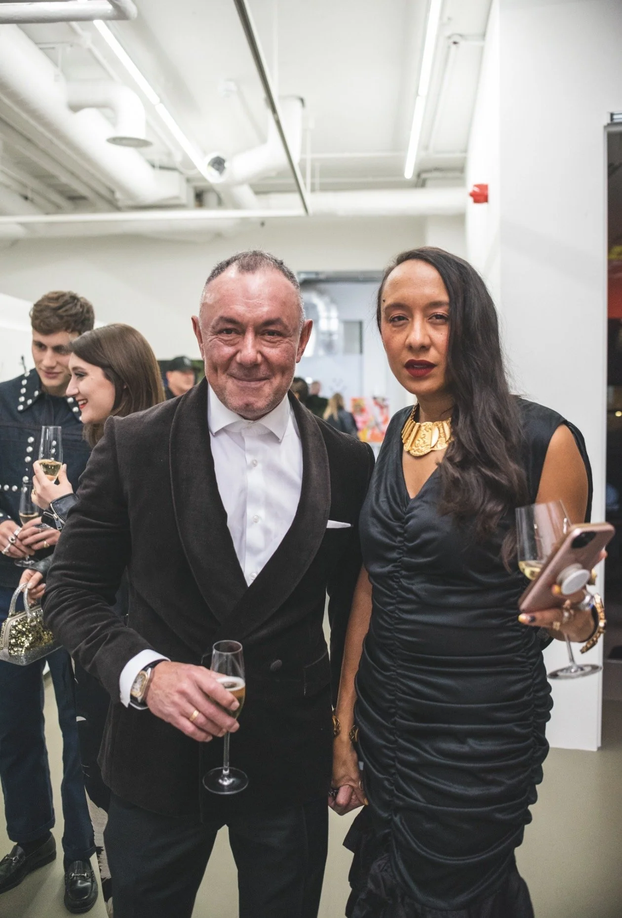 Man and woman dressed in formal wear holding glasses of champagne at an event.