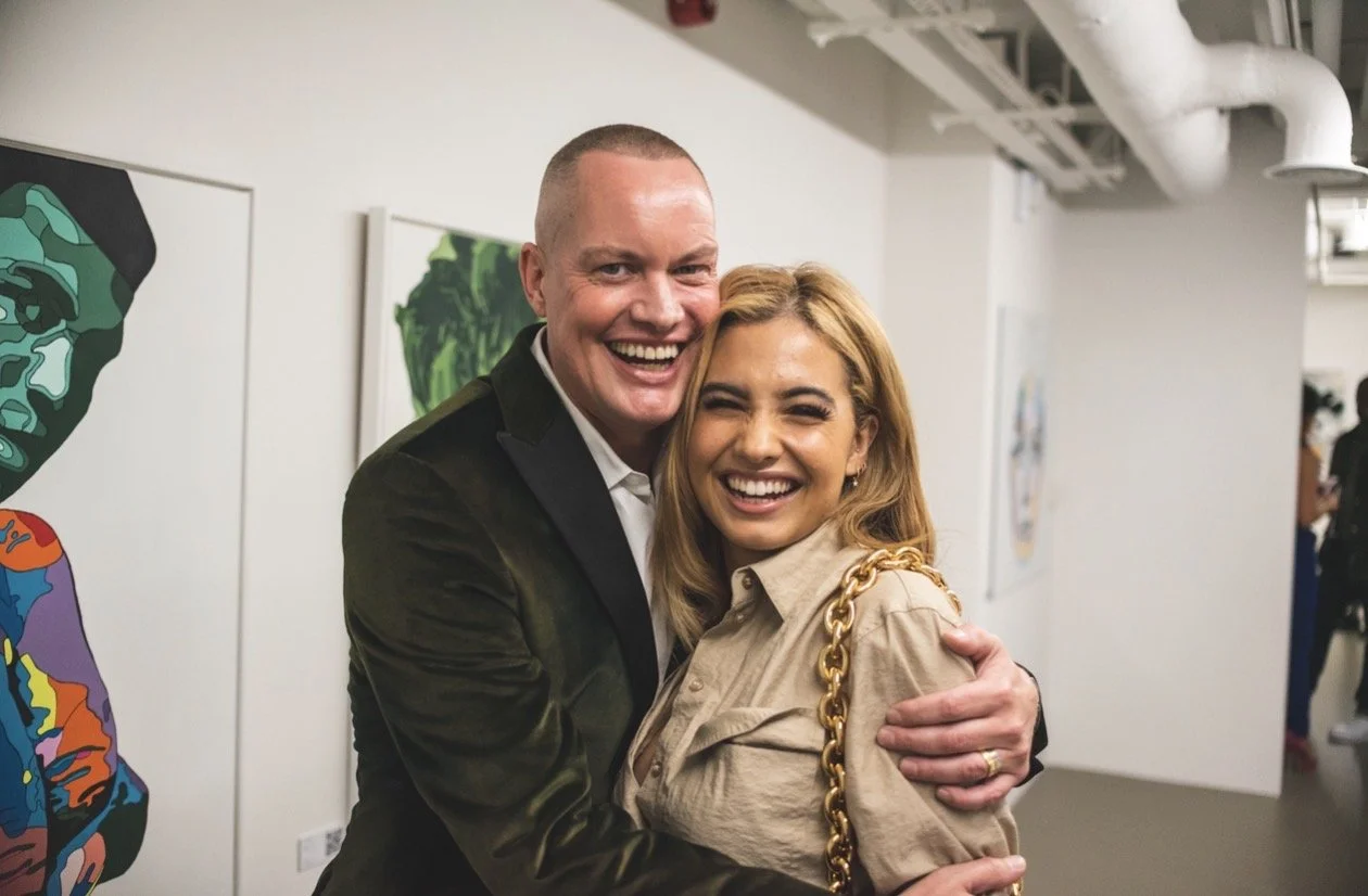 A man and woman hugging and smiling in an art gallery.