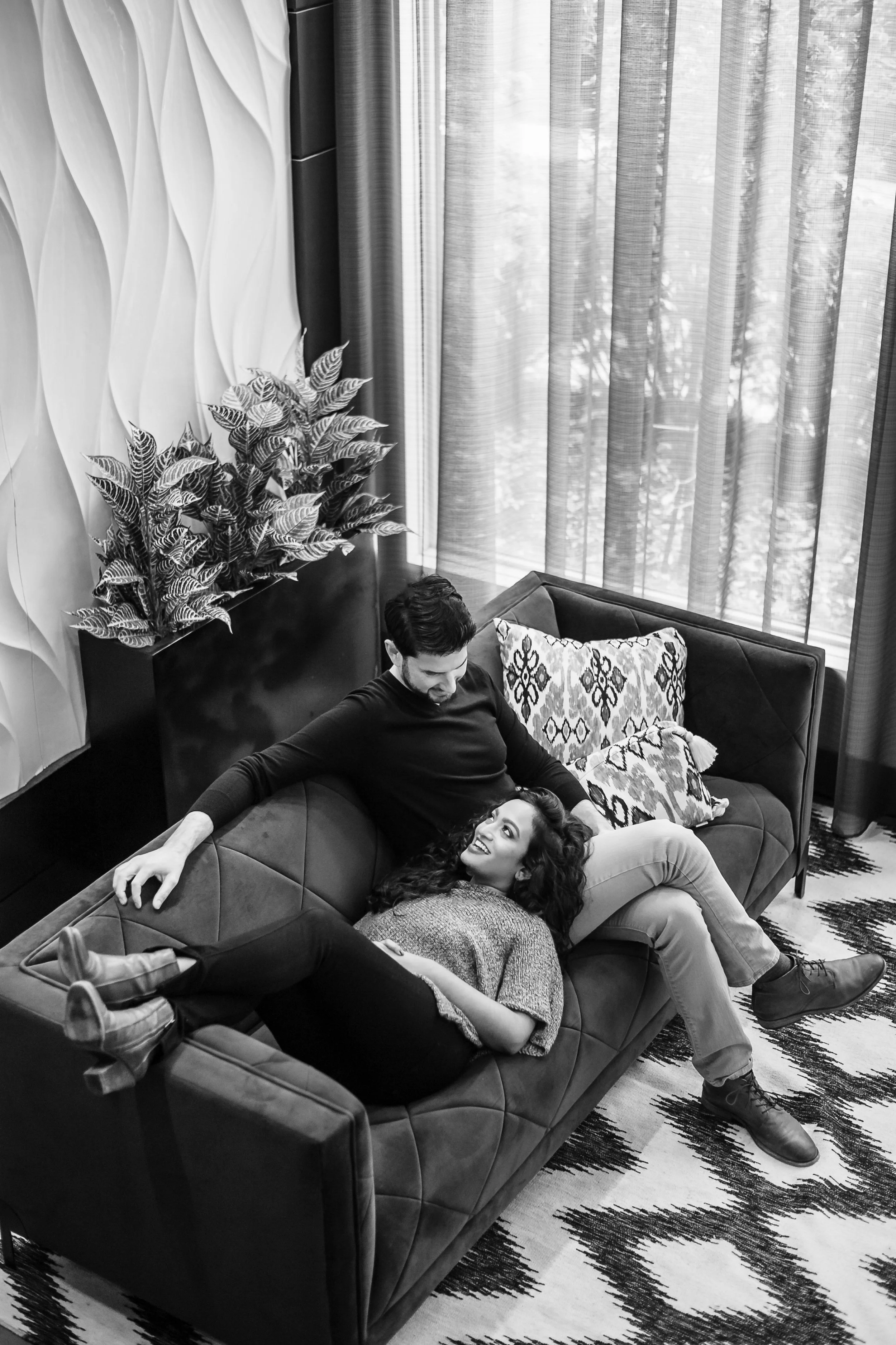 Engaged couple relaxing together on a leather sofa, black-and-white portrait by Jashim Jalal Studios