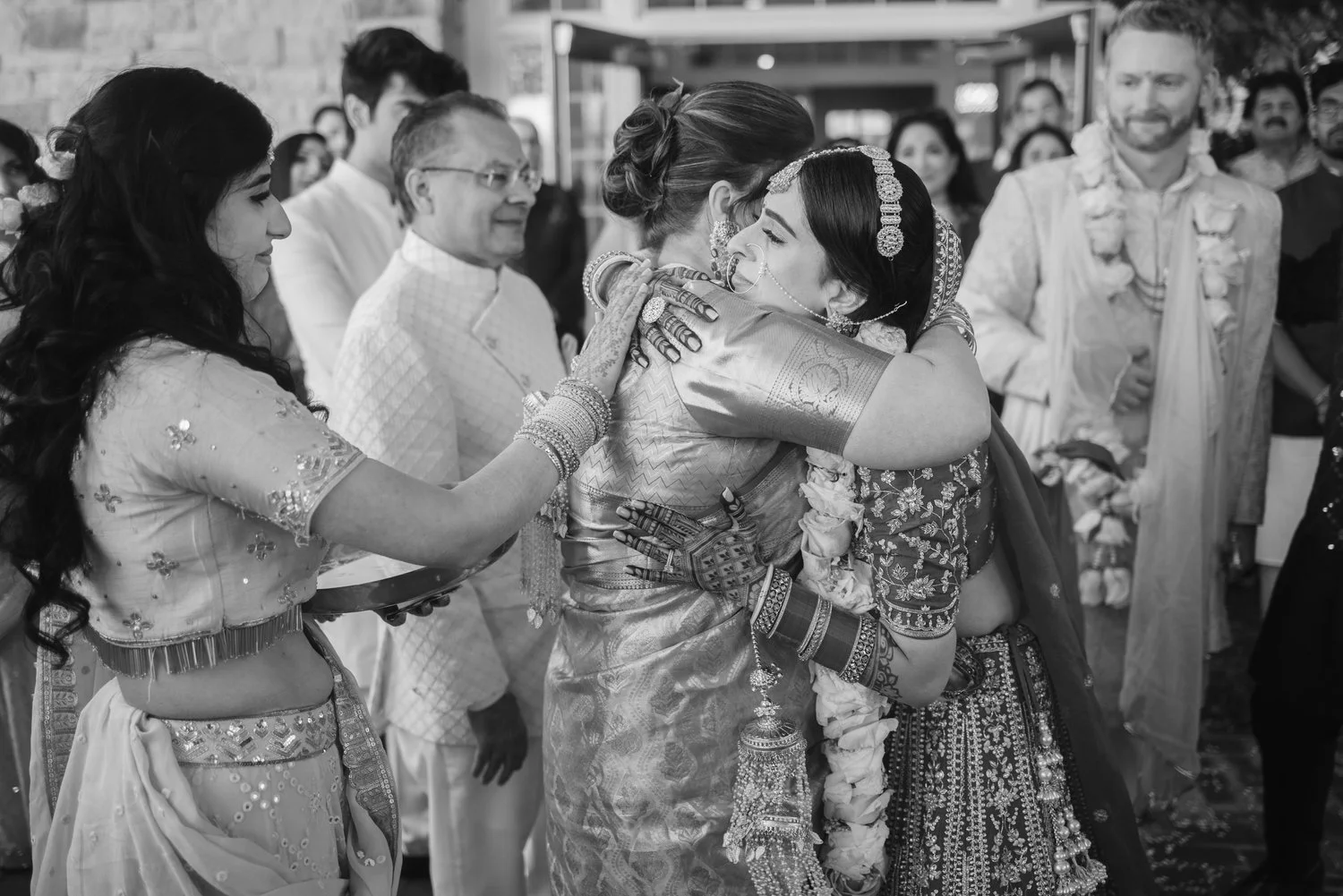 Bride embraces a woman during a ceremony as guests and groom look on